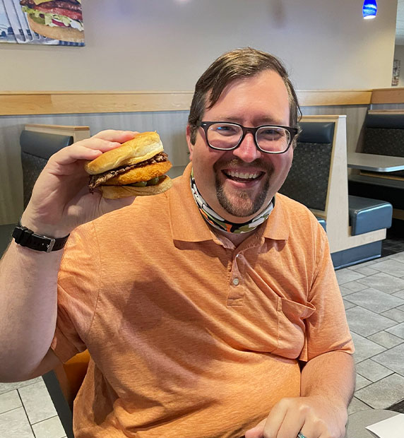 Man holding his CurderBurger and smiling.